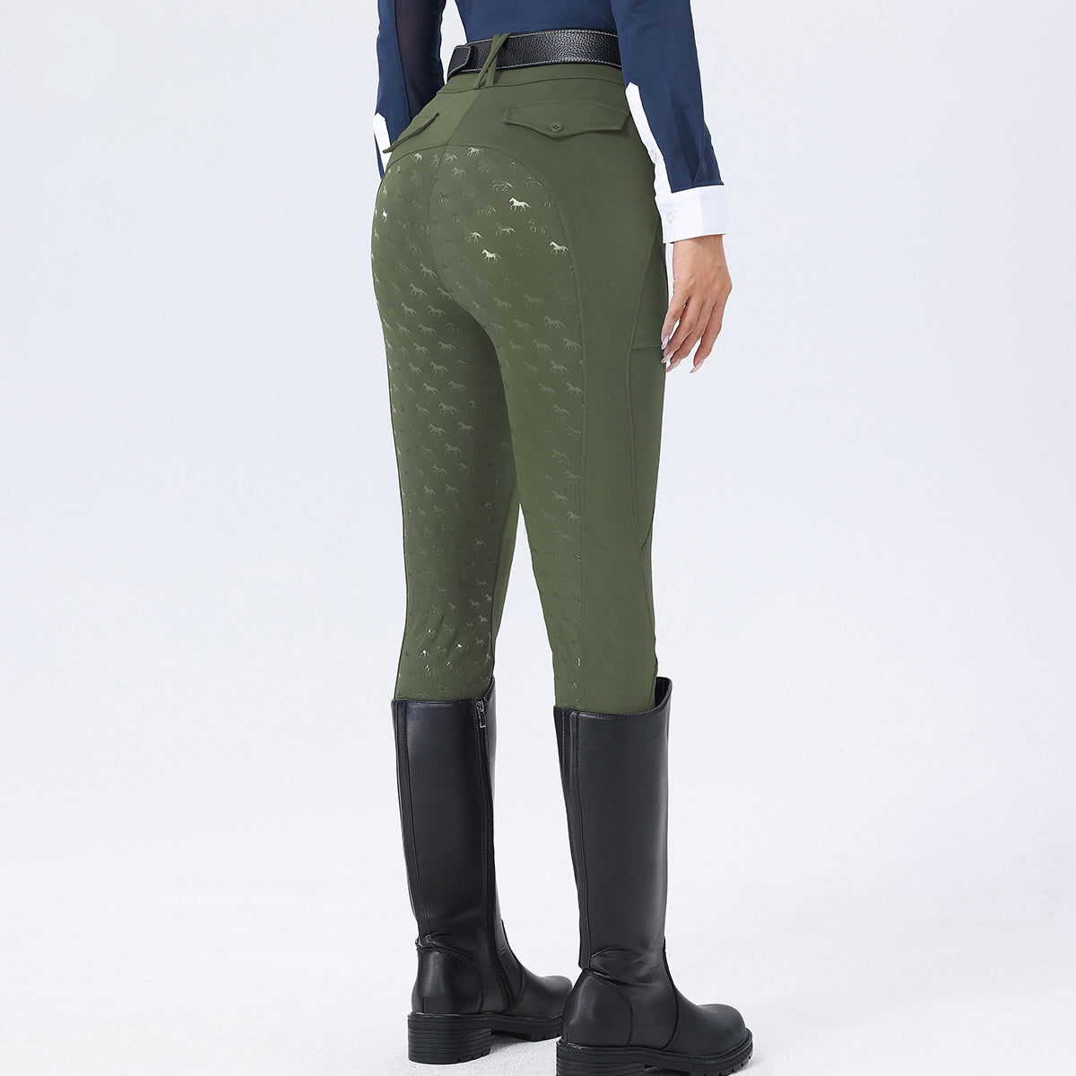 Person wearing green riding pants with patterned design, black riding boots, and a blue top on a white background.