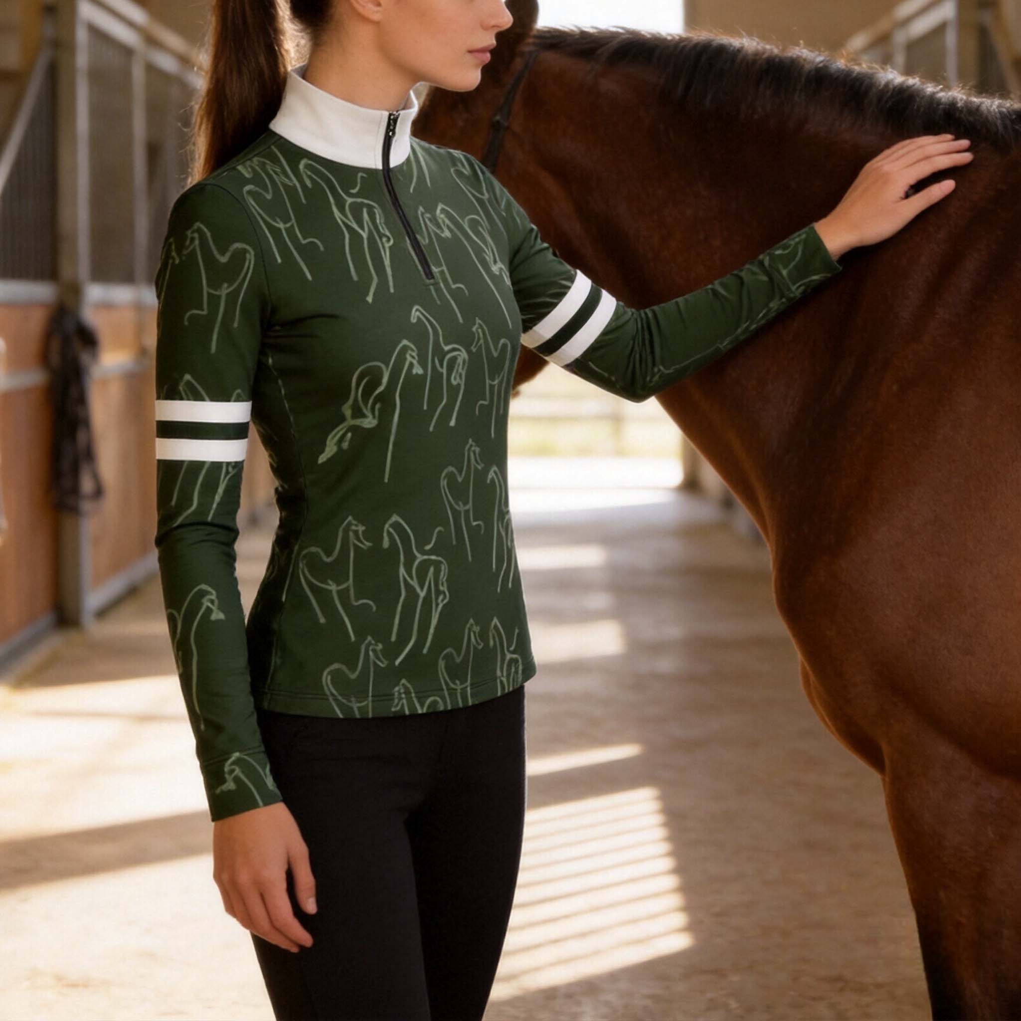 Side profile model touching brown horse inside sunlit indoor sand stable wearing dark forest green line horse white collar double stripe long sleeve riding top
