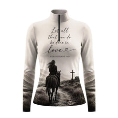 Model wearing muted monochrome spiritual mountain rider print riding top at outdoor equestrian show jumping arena with spectator stands
