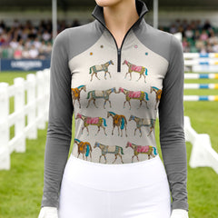 Model wearing whimsical colorful horse print riding top at outdoor equestrian show jumping arena with spectator stands