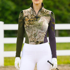 Model wearing olive plum color block art horse riding top at sunlit fenced equestrian pasture