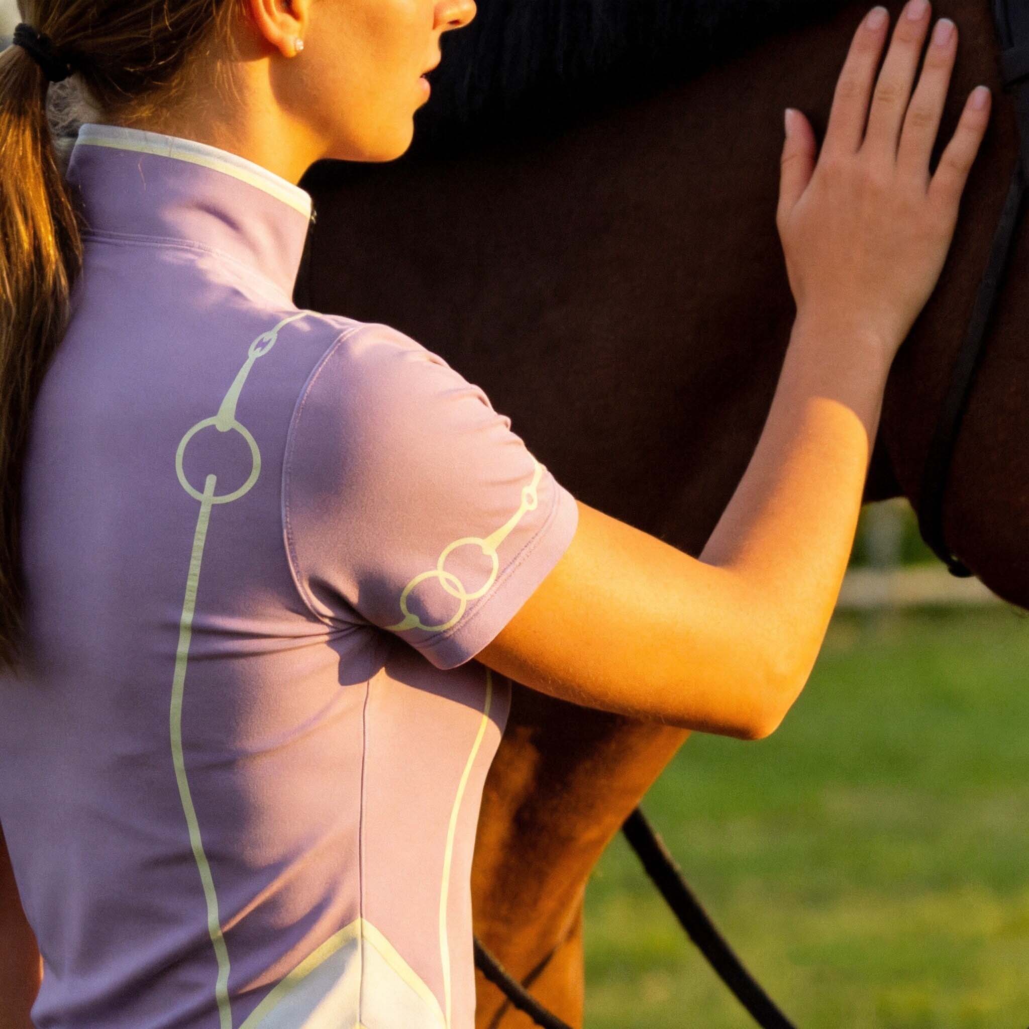 Close-up back view of model wearing lavender snaffle bit riding top petting a horse