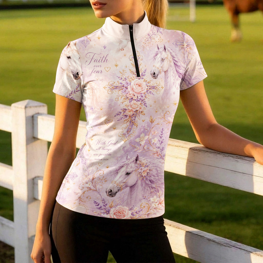 Model leaning on white wooden pasture fence wearing dusty lavender bible verse white horse floral cross short sleeve riding top in golden hour grass pasture
