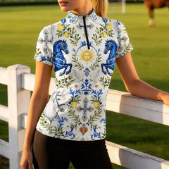 Golden‑hour pasture shot of female model leaning on white wooden fence in Sicilian folk‑art print short‑sleeve equestrian riding top