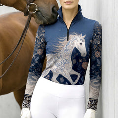 Model wearing midnight navy floral horse riding top leaning beside chestnut horse at stable grey wall