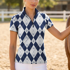 Model wearing the navy version of the Argyle & Horseshoe Print Short-Sleeve Riding Top at the stable, with a chestnut horse

