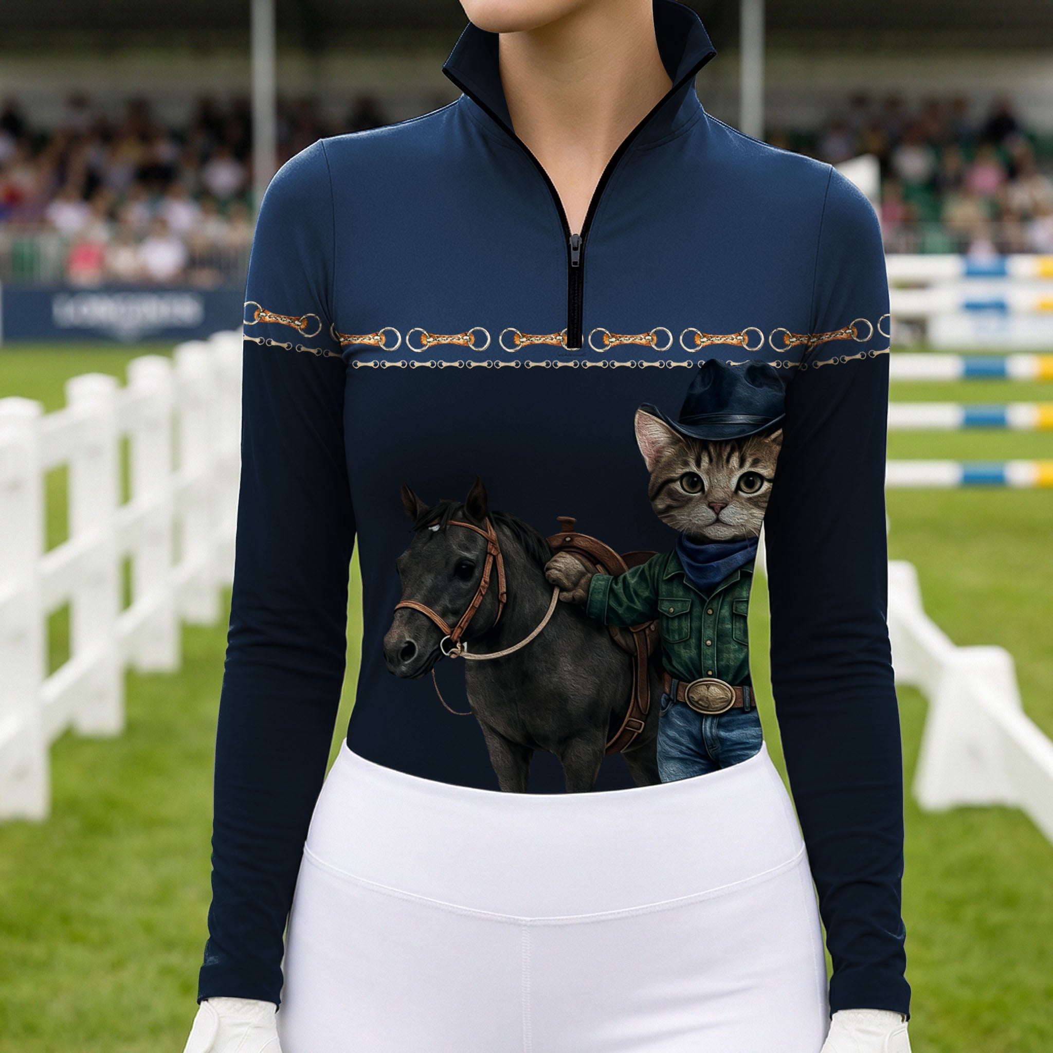 Equestrian show‑jumping arena close‑up model shot of rider in navy quarter‑zip long‑sleeve riding top with cowboy cat pony print