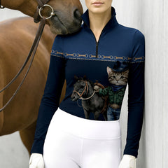 Lifestyle shot leaning beside brown horse of female equestrian wearing navy cowboy cat pony graphic long‑sleeve riding top