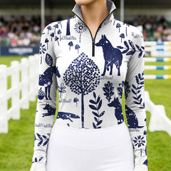 Model wearing minimalist navy wildlife forest print riding top at outdoor equestrian show jumping arena with spectator stands