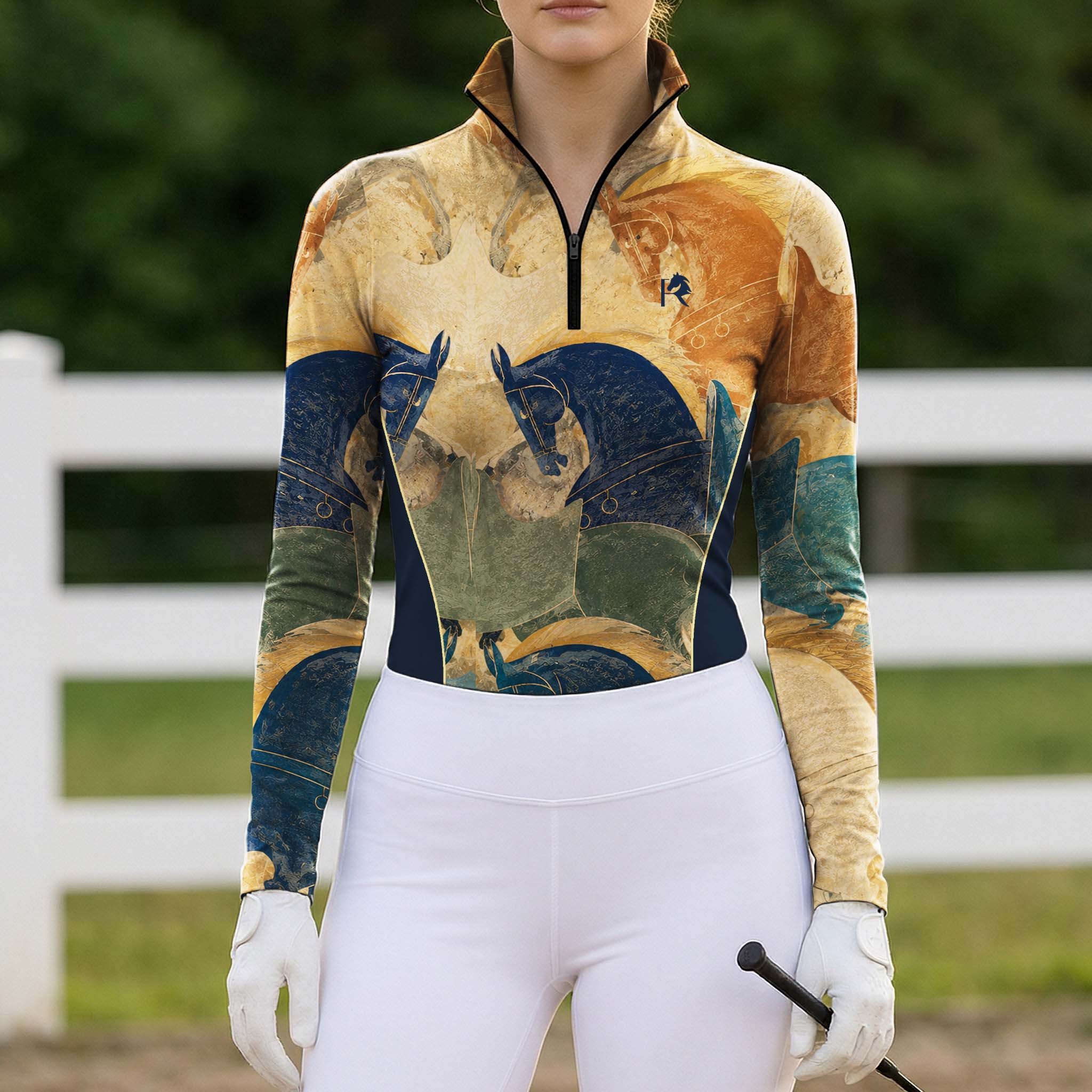 Outdoor pasture white‑fence lifestyle shot of female model wearing ochre‑gold fresco war‑horse art‑print long‑sleeve riding top