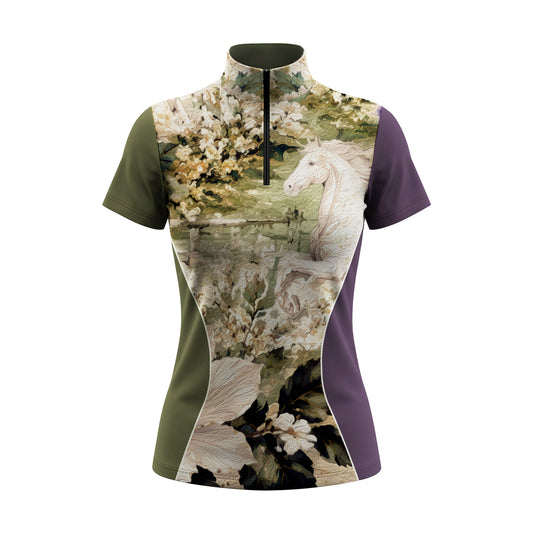 Side stretch close-up model shot in sunlit green pasture wearing olive & purple two-tone oil painting white horse floral panel short sleeve riding top
