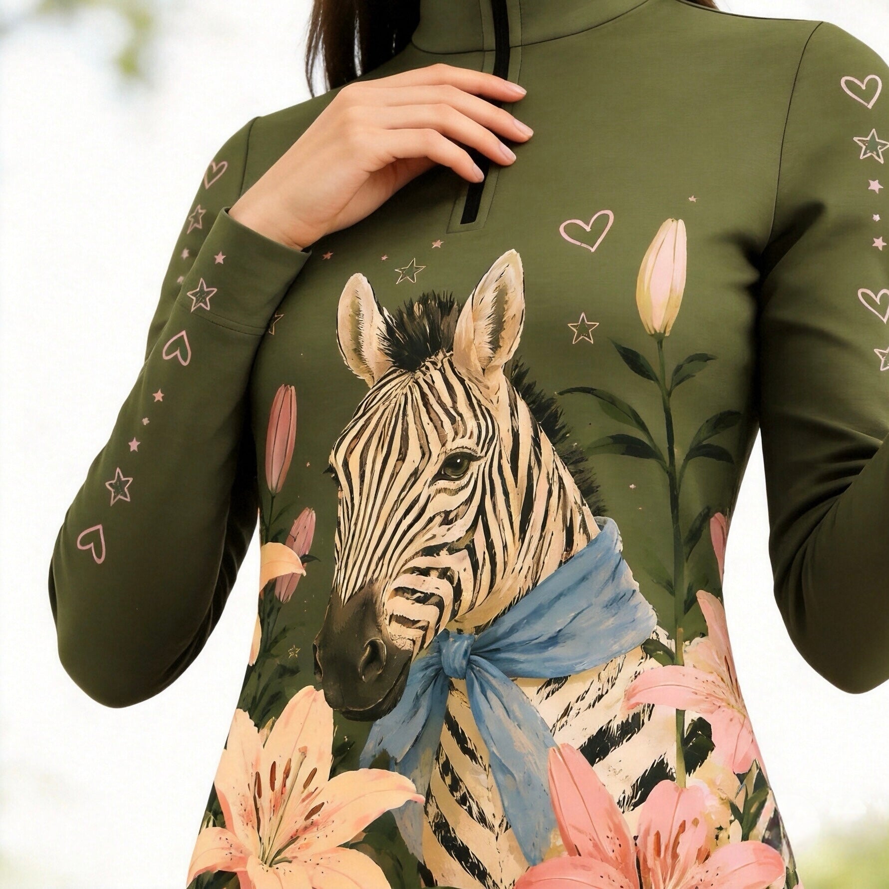 Close‑up detail shot showcasing front‑panel zebra‑and‑lily floral print on olive‑green long‑sleeve riding top