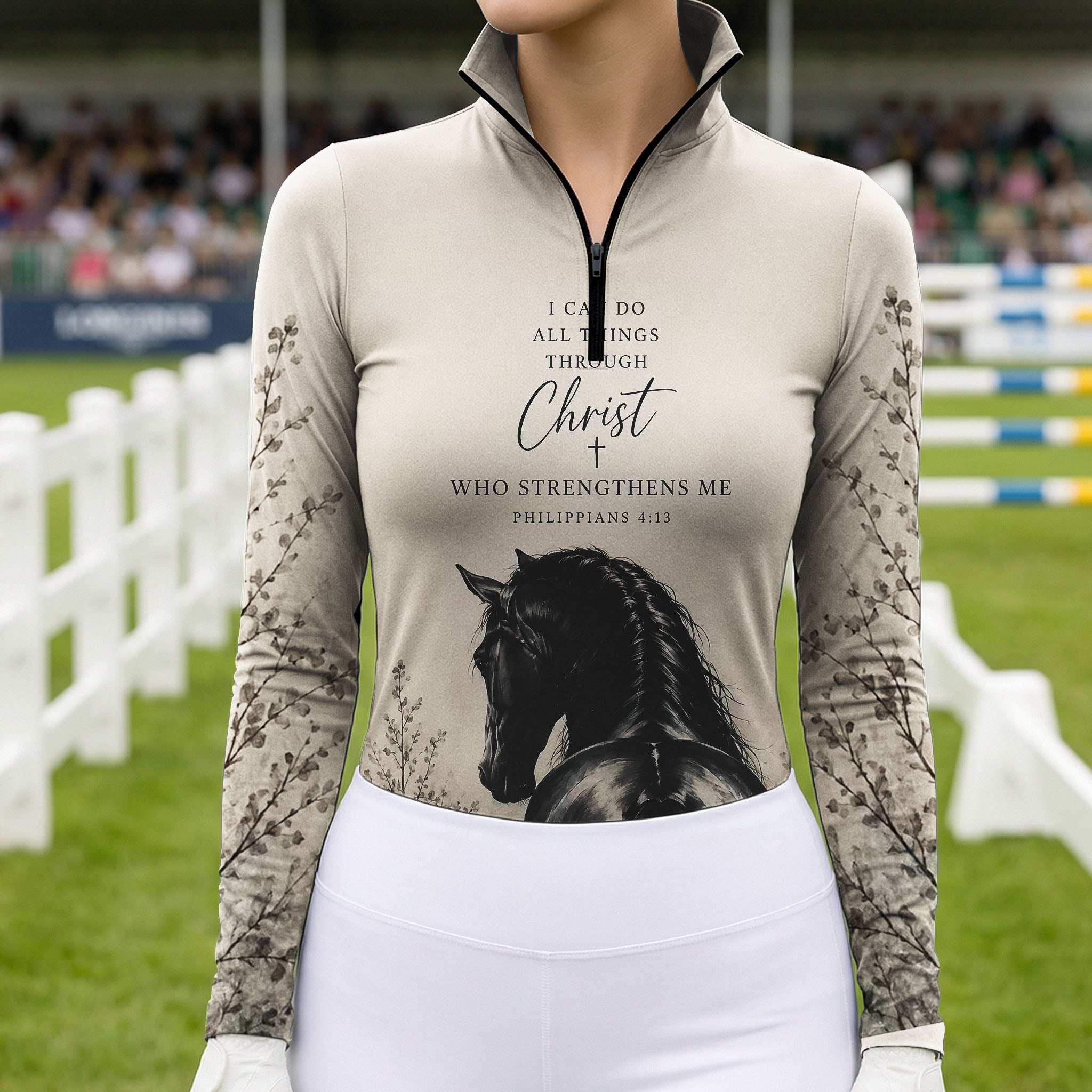Model wearing soft earth tone scripture horse print riding top at outdoor equestrian show jumping arena with spectator stands
