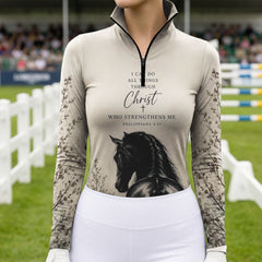 Model wearing soft earth tone scripture horse print riding top at outdoor equestrian show jumping arena with spectator stands
