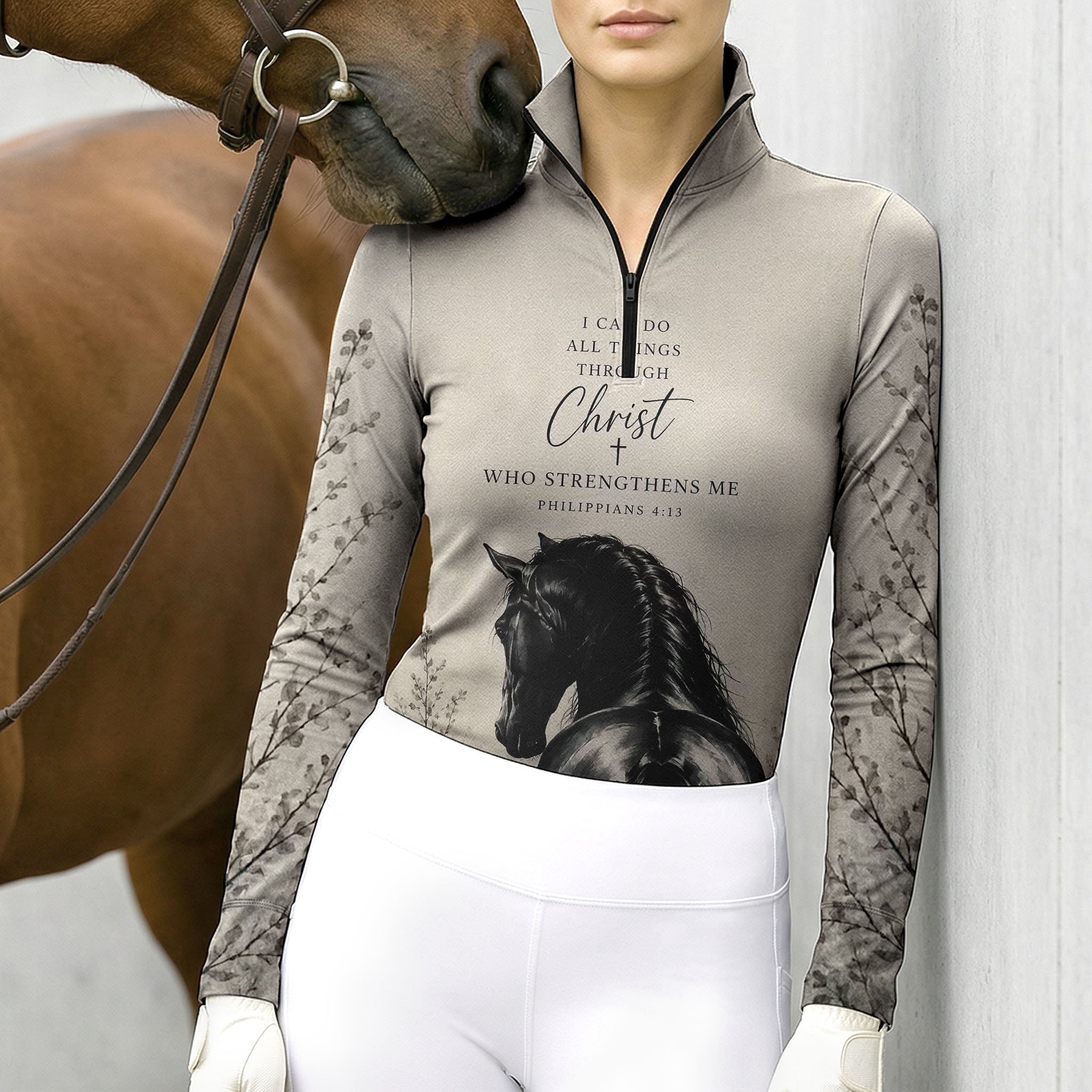Model leaning against light grey stable wall beside chestnut horse wearing muted taupe bible verse black stallion branch riding top
