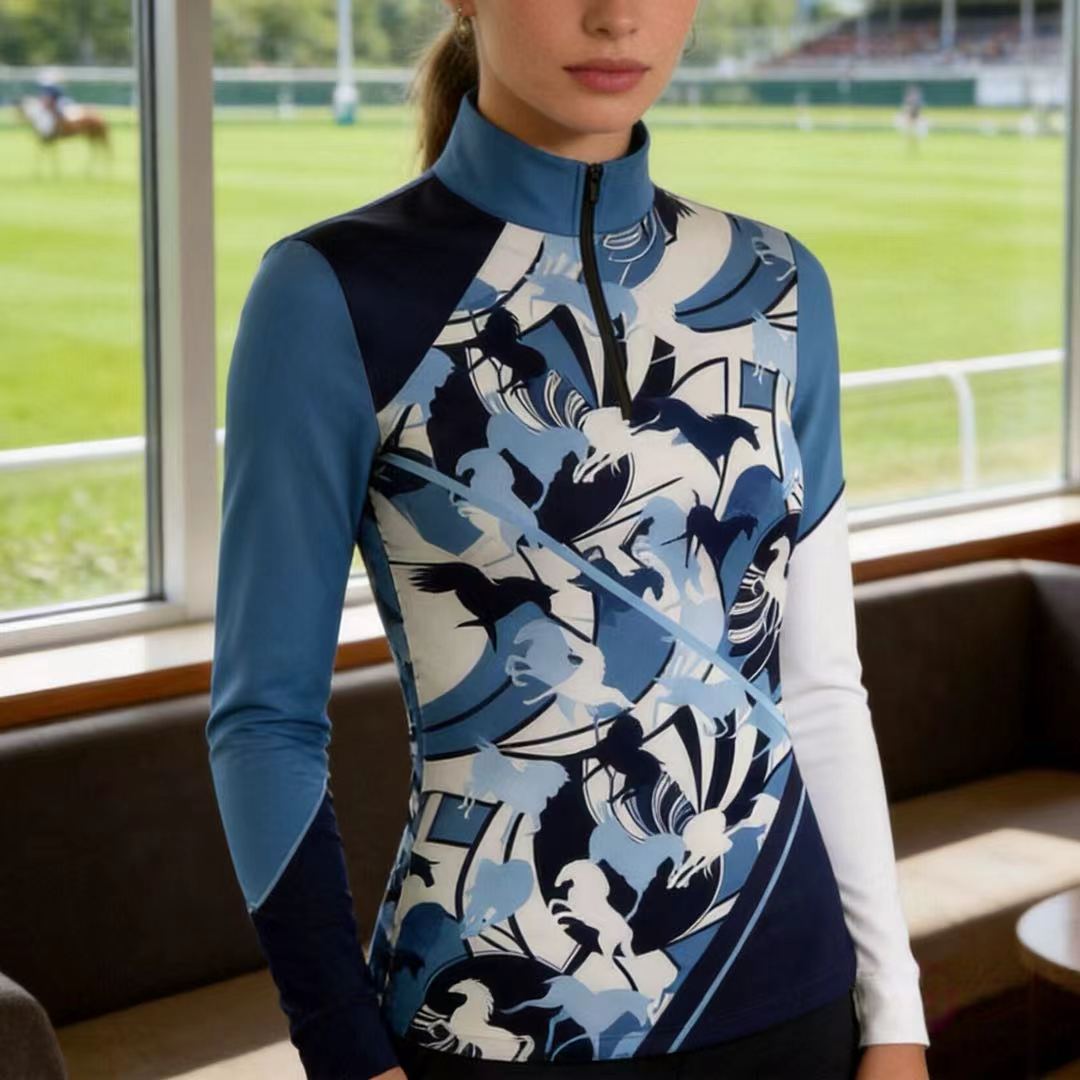Model wearing the RIDER ATELIER Abstract Blue Horse Silhouette Riding Top by a racetrack grandstand, showcasing the print’s dynamic design
