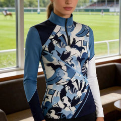 Model wearing the RIDER ATELIER Abstract Blue Horse Silhouette Riding Top by a racetrack grandstand, showcasing the print’s dynamic design
