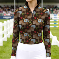 Woman wearing RIDER ATELIER cute cartoon horse dark brown quarter-zip top at the show jumping arena