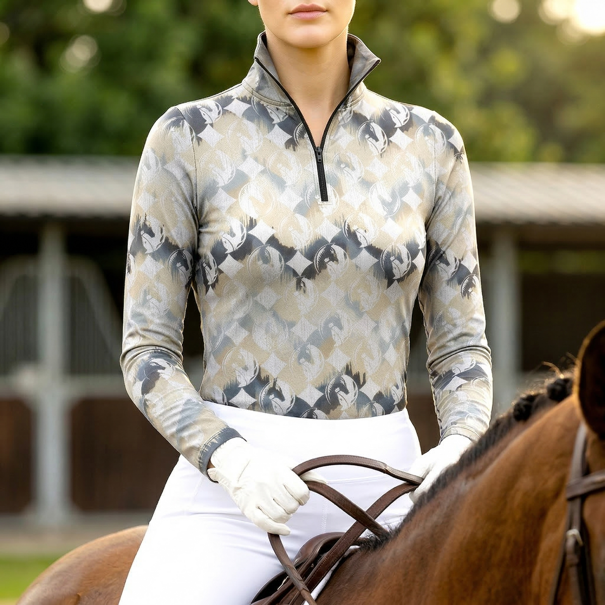 Woman wearing RIDER ATELIER diamond horse silhouette equestrian quarter-zip top in taupe gray, riding a chestnut horse at the equestrian stable
