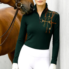 Model wearing the RIDER ATELIER Forest Green Bit & Bridle Print Riding Top at the stable, with a chestnut horse, highlighting the print’s polished texture

