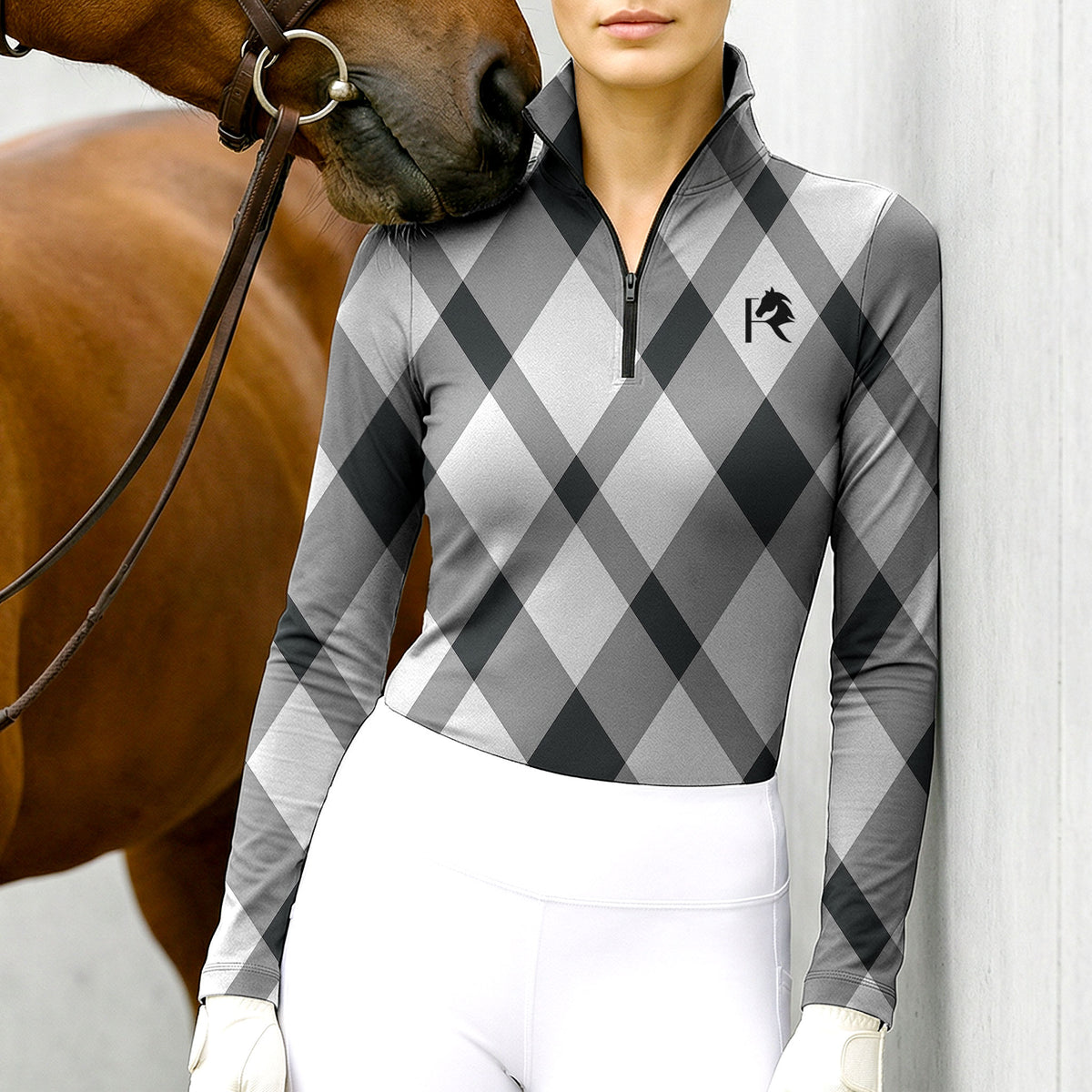 Woman wearing RIDER ATELIER gray argyle quarter-zip top with a chestnut horse