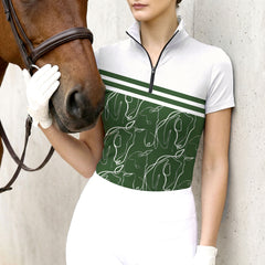 Woman wearing the RIDER ATELIER Green Abstract Horse Line Art Riding Top at the stable, with a chestnut horse nuzzling her hand, showcasing the print and tailored fit
