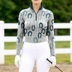 Woman wearing RIDER ATELIER horseshoe print gray teal quarter-zip top at the outdoor pasture