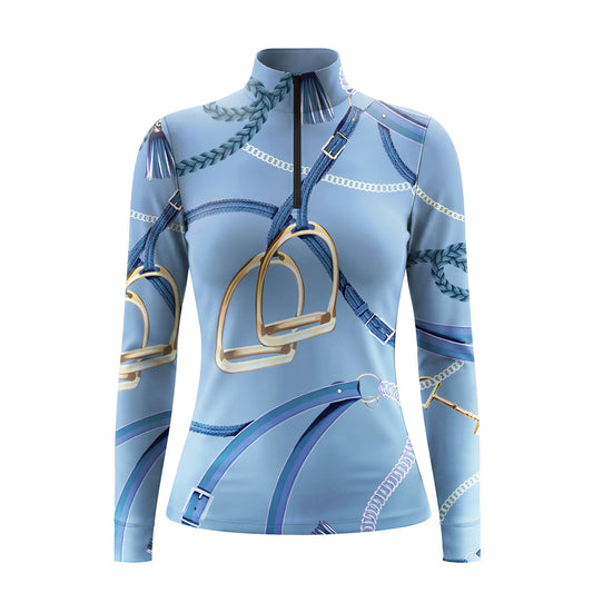 Studio shot of the RIDER ATELIER Light Blue Equestrian Tack Print Quarter-Zip Riding Top, showing full stirrup, rein, and chain print pattern, quarter-zip collar, and fabric texture against a clean white background

