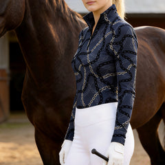 Woman wearing RIDER ATELIER luxury chain link quarter-zip top with a horse in the stable