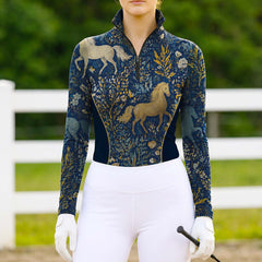 Model wearing the RIDER ATELIER Midnight Blue Mythical Horse & Floral Riding Top at a sunlit pasture, holding a riding crop
