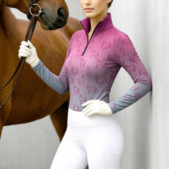 Woman wearing RIDER ATELIER ombre line art horse equestrian quarter-zip top in pink-gray gradient at the barn, holding horse reins