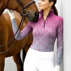 Woman wearing RIDER ATELIER ombre line art horse equestrian quarter-zip top in pink-gray gradient at the barn with a chestnut horse
