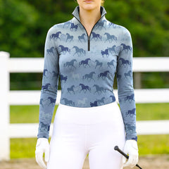 Woman wearing RIDER ATELIER ombre multi horse silhouette light blue quarter-zip top at the outdoor pasture