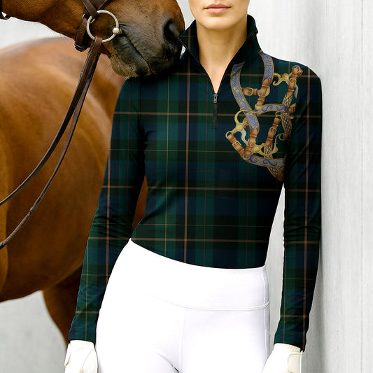 Woman wearing RIDER ATELIER plaid snaffle bit green quarter-zip top at the barn with a chestnut horse
