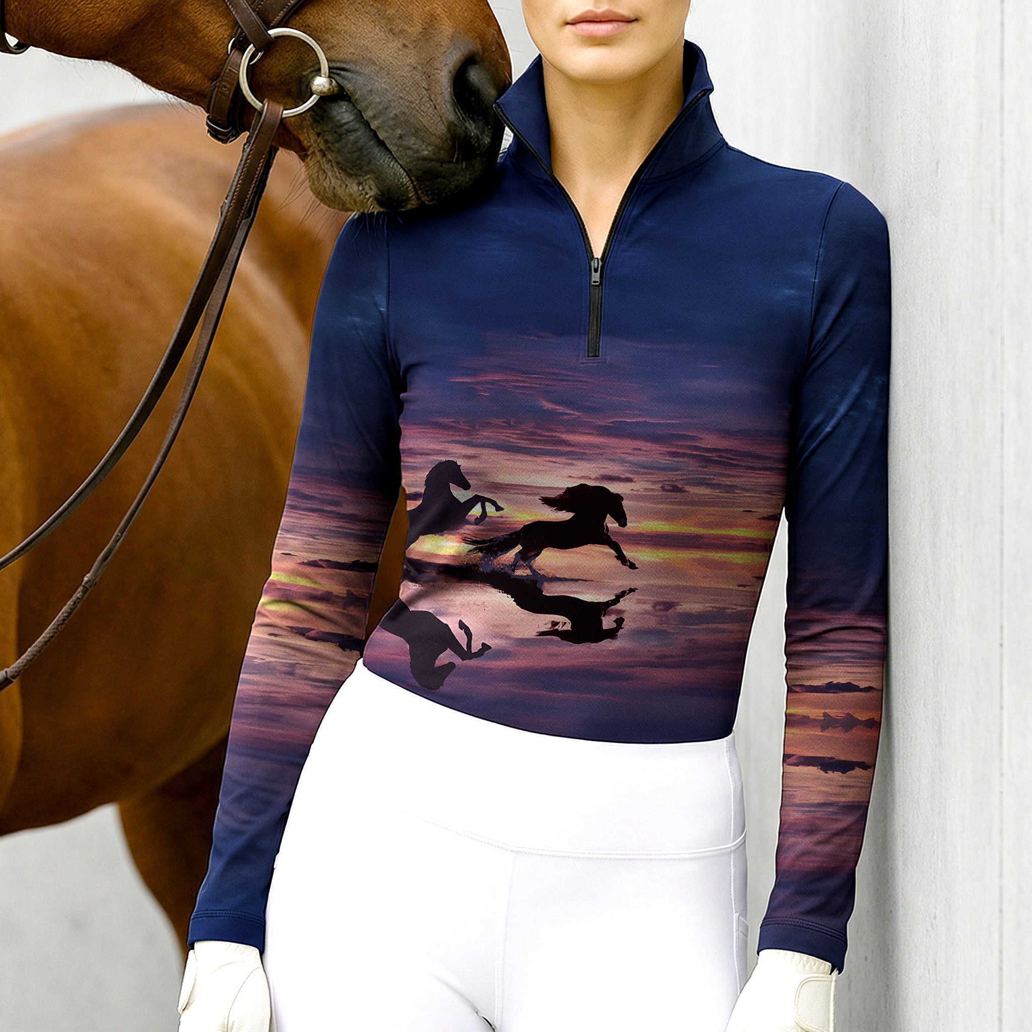 Woman wearing RIDER ATELIER sunset horse silhouette navy quarter-zip top with a chestnut horse