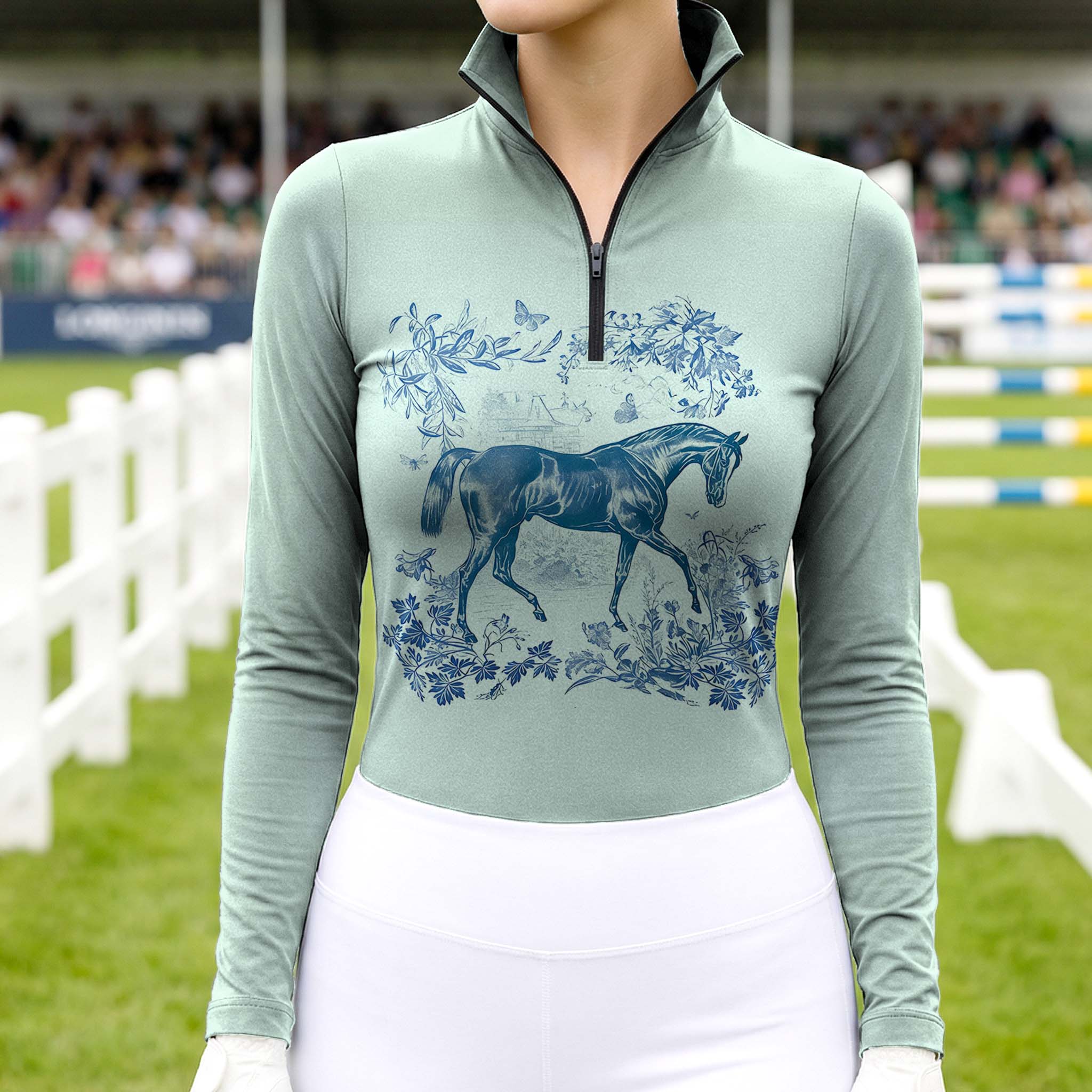 Woman wearing RIDER ATELIER Toile de Jouy horse sage green quarter-zip top at the show jumping arena
