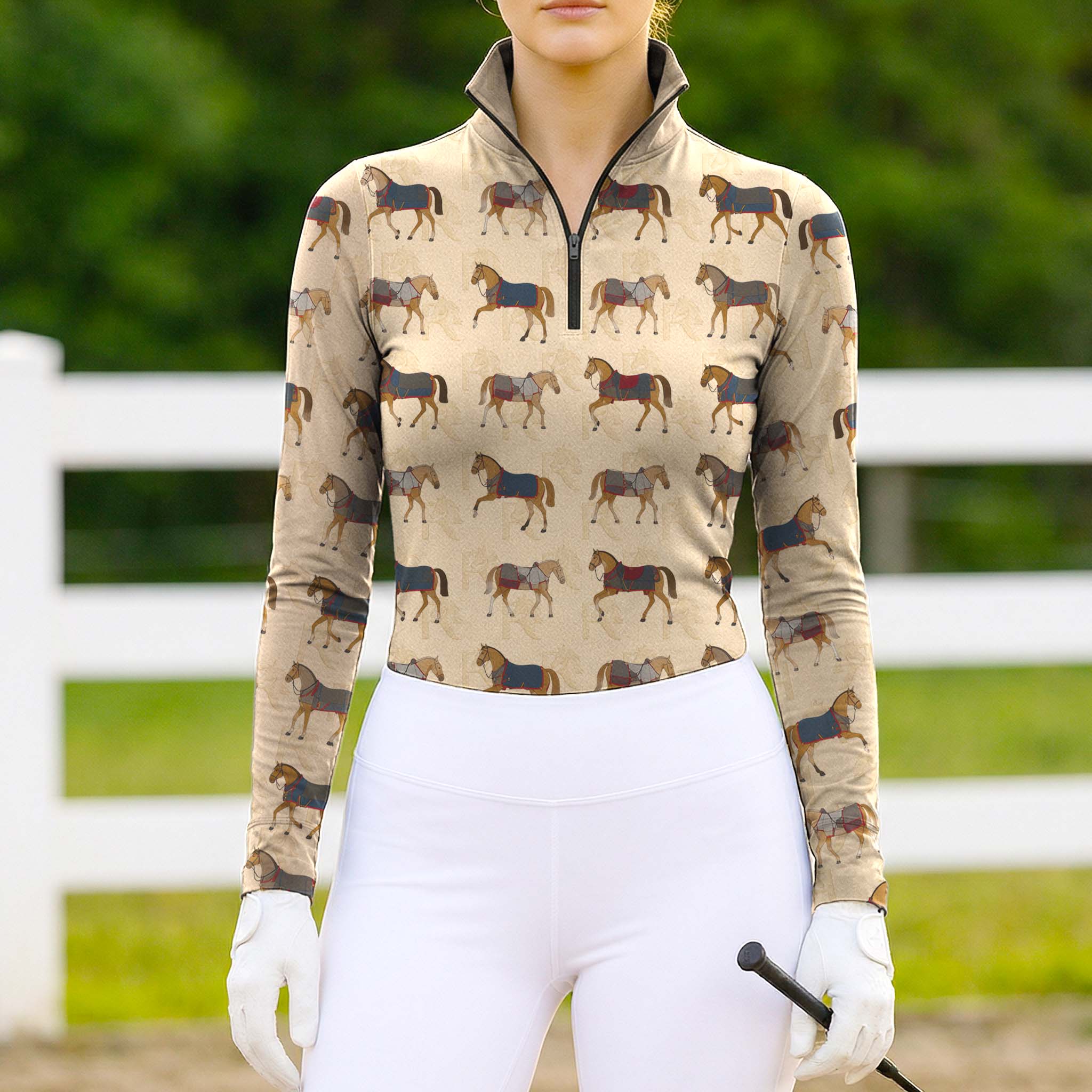 Model wearing the RIDER ATELIER Vintage Show Horse Print Long-Sleeve Riding Top at a sunlit pasture, holding a riding crop
