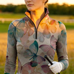 Woman wearing RIDER ATELIER watercolor butterfly beige quarter-zip top walking in the field at sunset