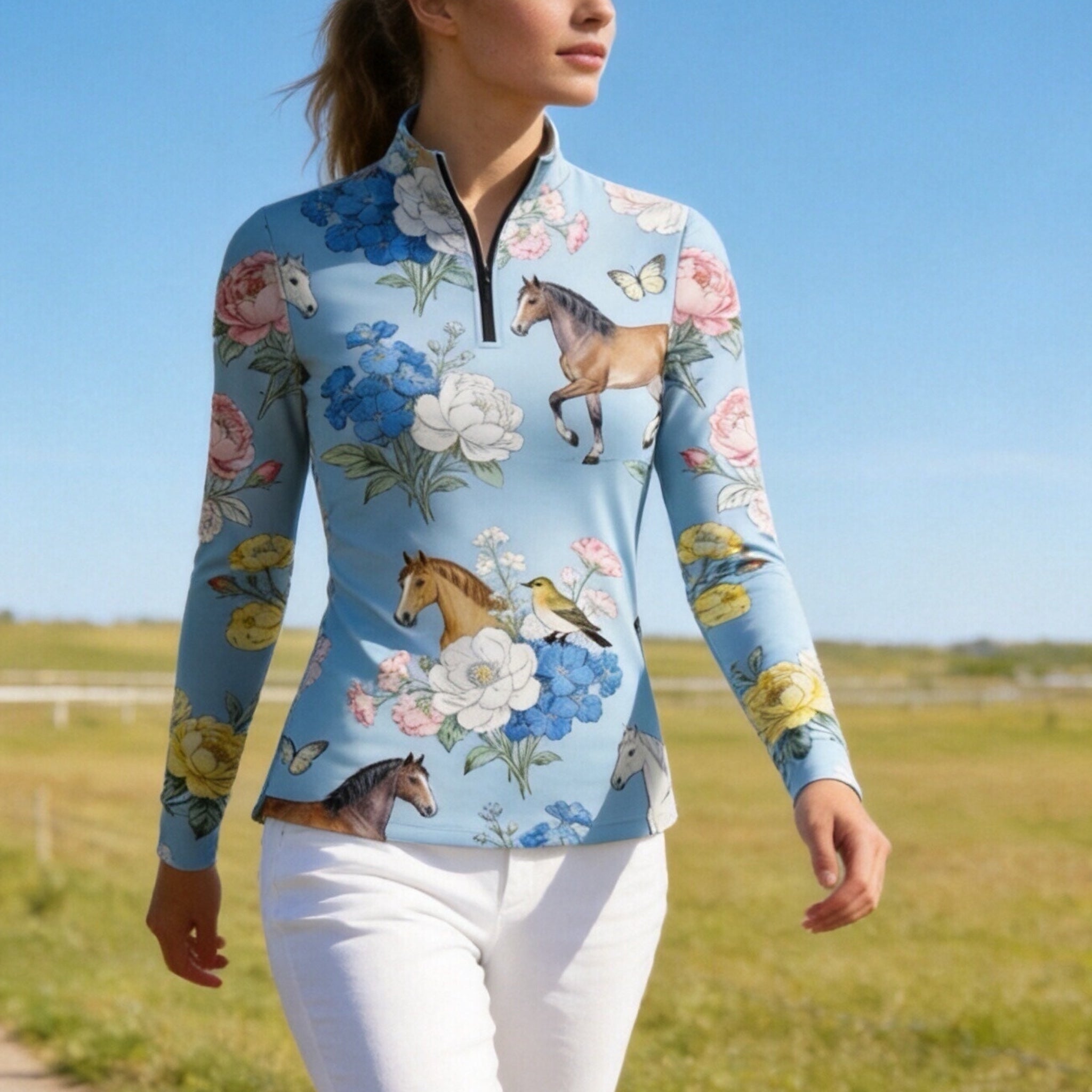 Model wearing the RIDER ATELIER Watercolor Floral Horse Print Riding Top while walking in a sunlit pasture
