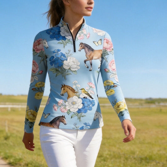 Model wearing the RIDER ATELIER Watercolor Floral Horse Print Riding Top while walking in a sunlit pasture
