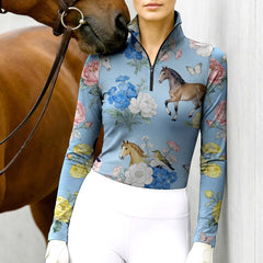 Model wearing the RIDER ATELIER Watercolor Floral Horse Print Riding Top at the stable, with a chestnut horse, highlighting the print’s delicate texture
