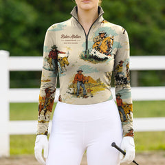 Model wearing the RIDER ATELIER Vintage Western Cowboy Print Riding Top at a sunlit pasture, holding a riding crop
