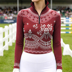 Model wearing burgundy lace floral horse riding top at outdoor equestrian jump arena