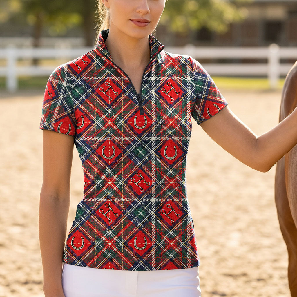 Model wearing classic tartan equestrian print riding top beside brown horse on sunlit dirt arena