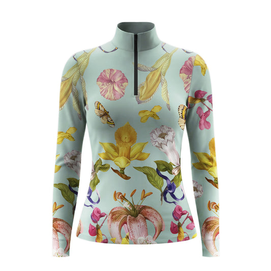 Model leaning against light grey stable wall beside chestnut horse wearing sage vintage tropical flower butterfly riding top
