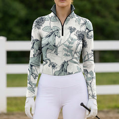 Outdoor farm fence arena shot of female rider wearing off‑white sketch horse wild botanical floral print long‑sleeve riding top