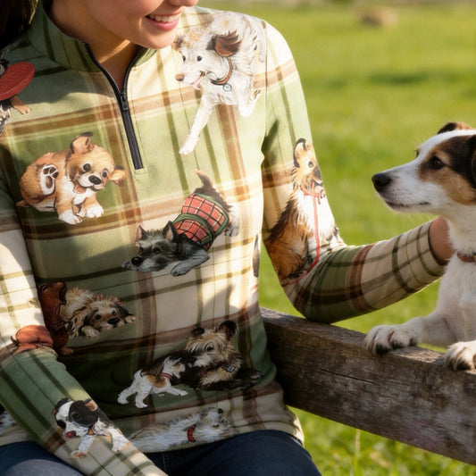 Sunlit green grass pasture white rail fence shot of model holding white riding gloves showcasing cozy green beige country tartan plaid multi-breed playful puppy dog full print equestrian long sleeve top