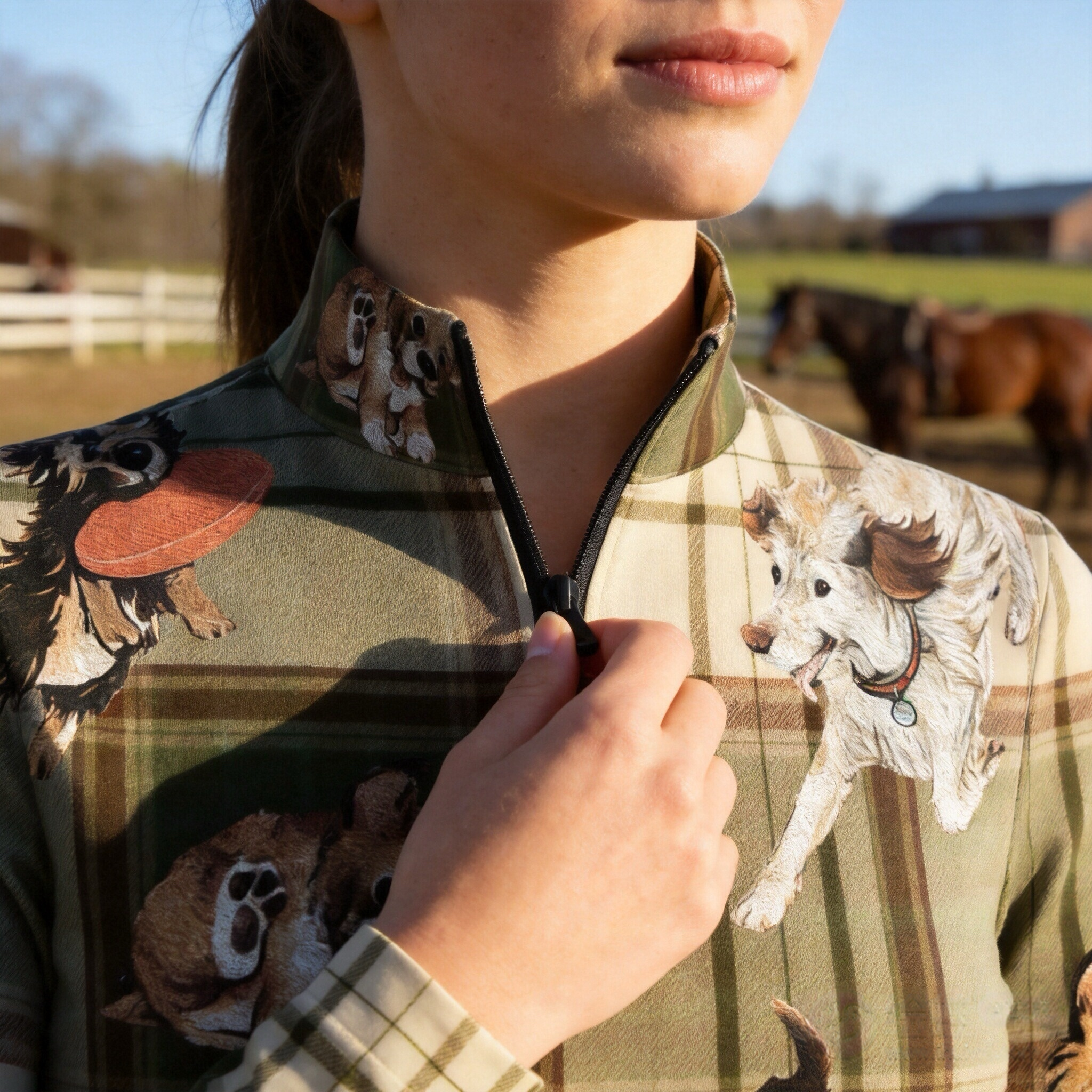 Warm sunlit countryside stable outdoor close-up shot focusing on stand collar, black half-zip and front tartan plaid multi-breed puppy dog graphic riding top