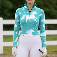 Sunlit green pasture white rail fence shot of model holding riding crop showcasing dreamy starry sky unicorn print riding top
