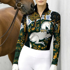 Model wearing unicorn tapestry riding top beside brown horse leaning against grey wall